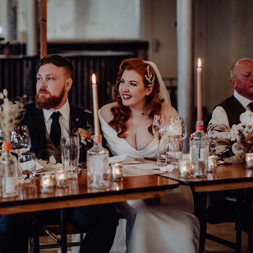 Bride and groom smiling during the wedding speeches at Holmes Mill 
