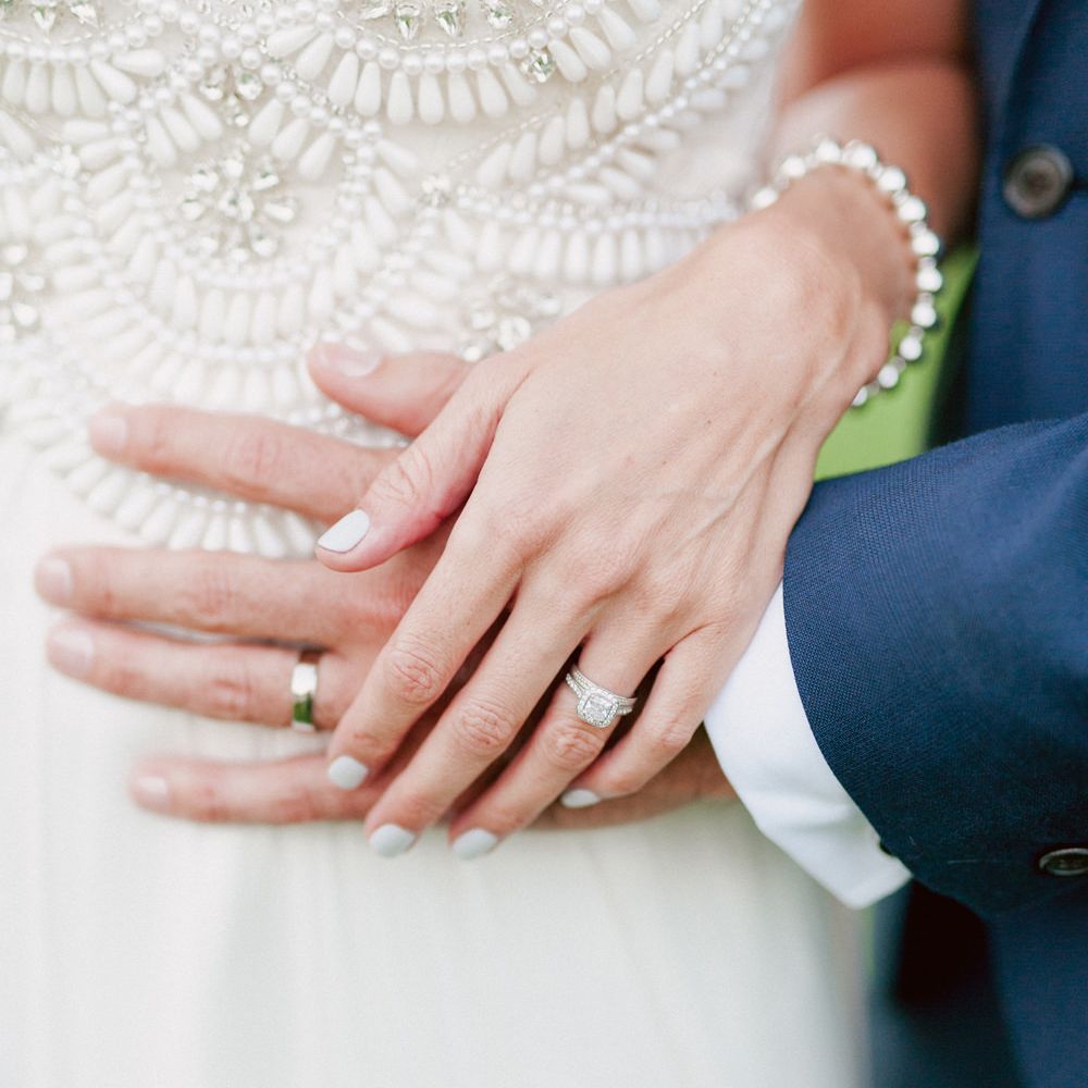 Bride places hand over grooms to show wedding rings