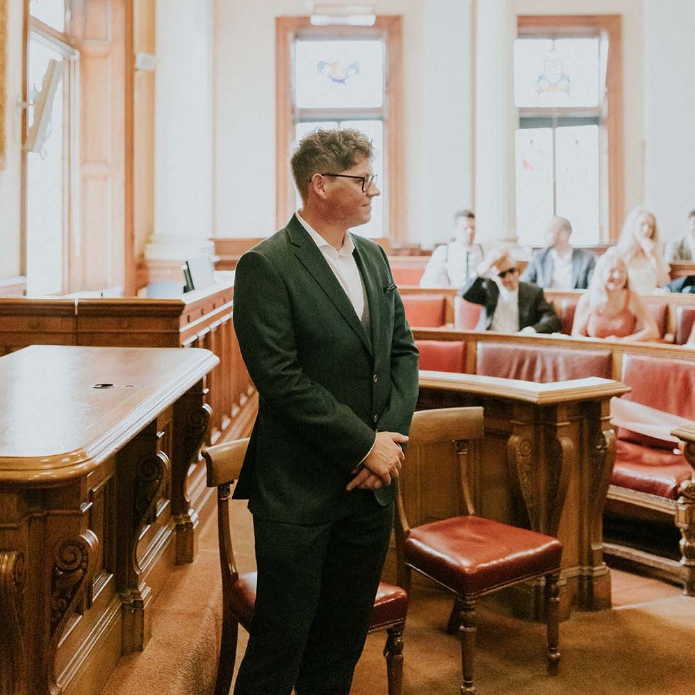 Groom awaits his bride at the altar whilst wearing green jacket and white Nike trainers