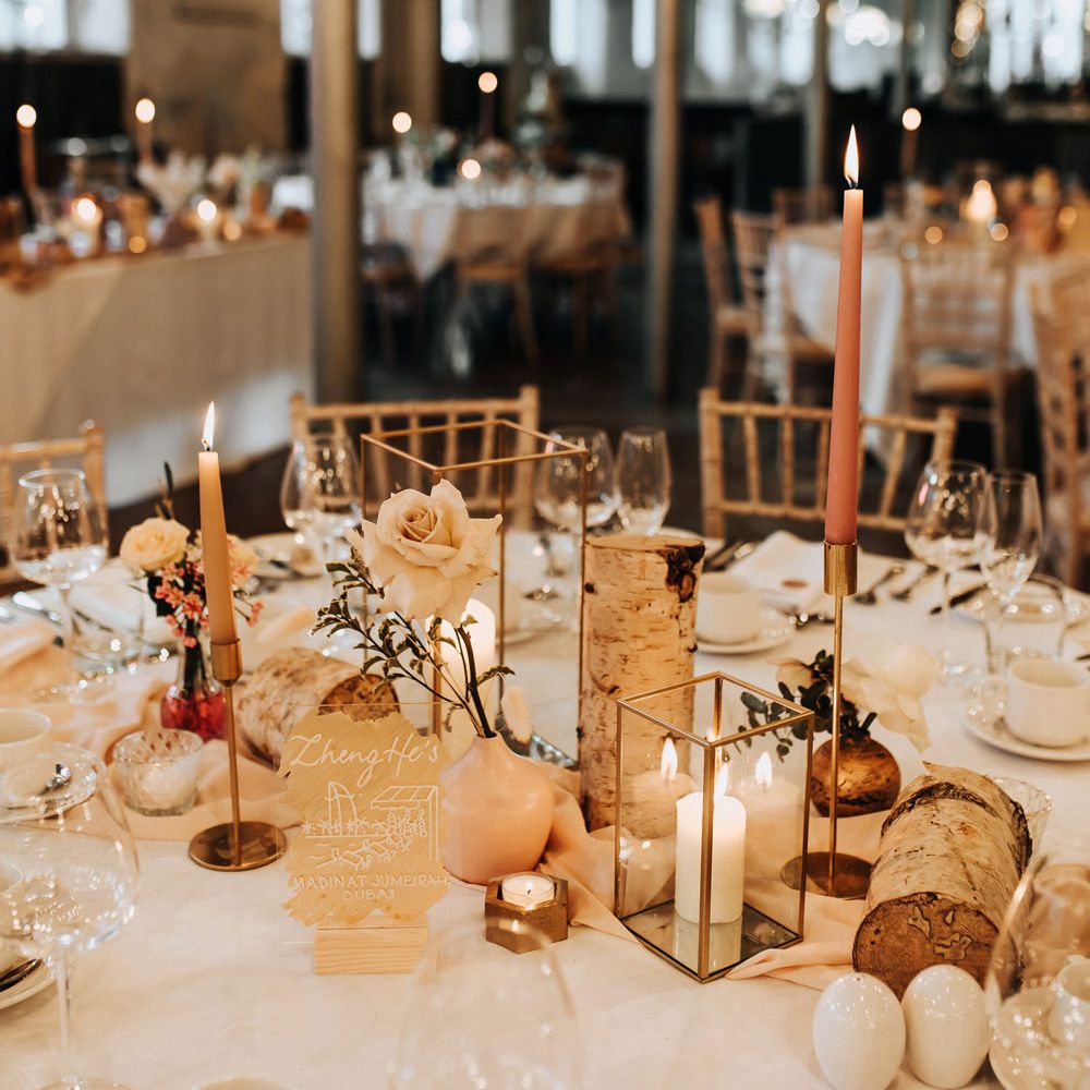 White round wedding tables with roses, candles and pink dinners candles at Industrial wedding venue
