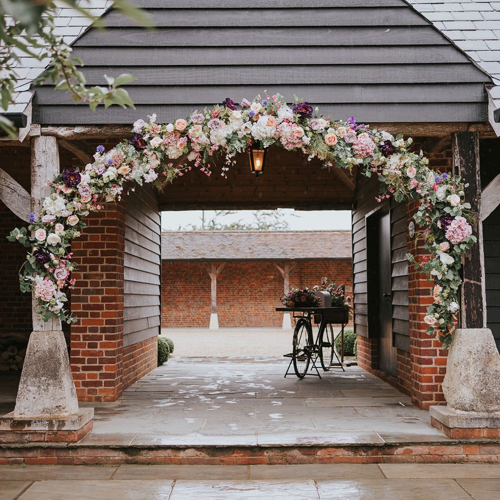 Country house venue with flower arch made up of assorted flowers and colours