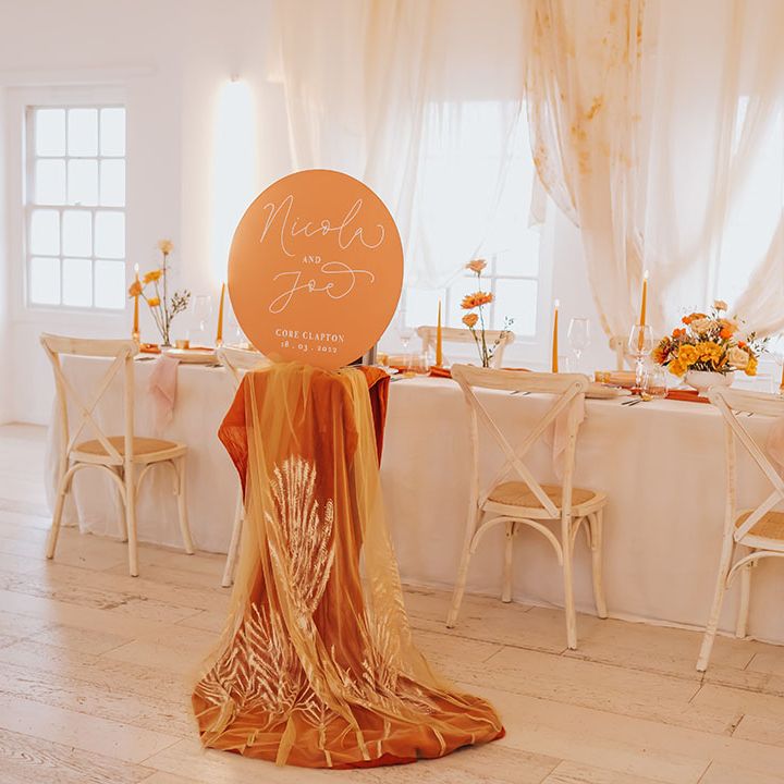 intimate golden wedding table scape with drapes and linens and orange wedding sign 