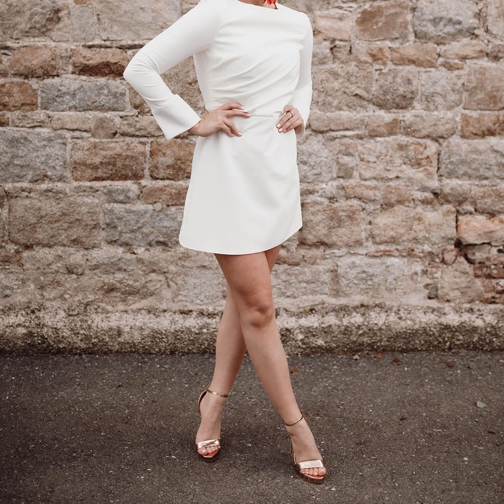 Stylish bride in a short wedding dress with red statement earrings and gold platform shoe bridal accessories 