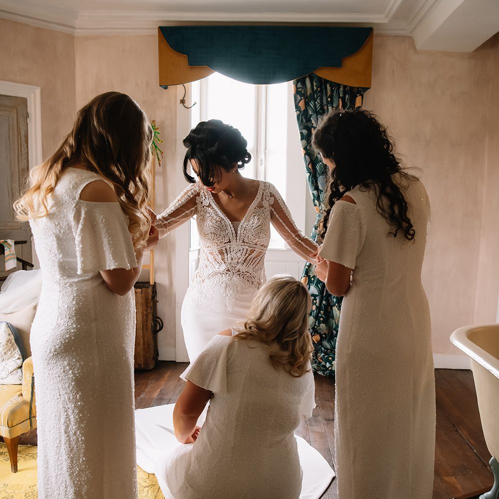 Bridesmaids help the bride get ready for the big day with finishing touches 