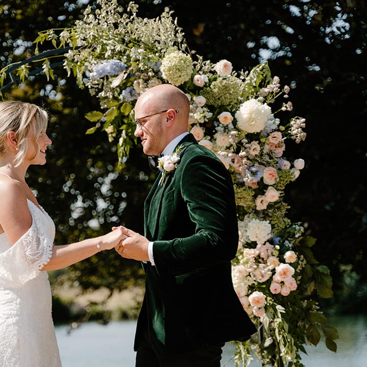 Groom wears green velvet black tie whilst marrying his bride in outdoor ceremony 