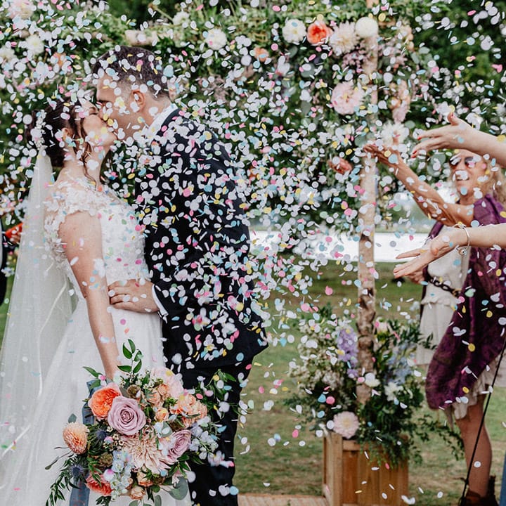 Colourful pastel wedding confetti moment for the bride and groom as they share a kiss at Culden Faw Estate