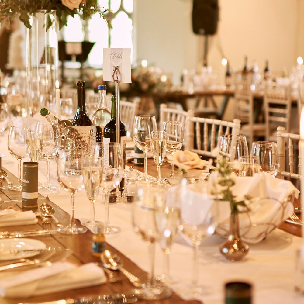 Classic rustic wedding tablescape with white table runners and rose and foliage centrepieces with fairy lights in Cluny Castle wedding reception room - wedding venues Scotland