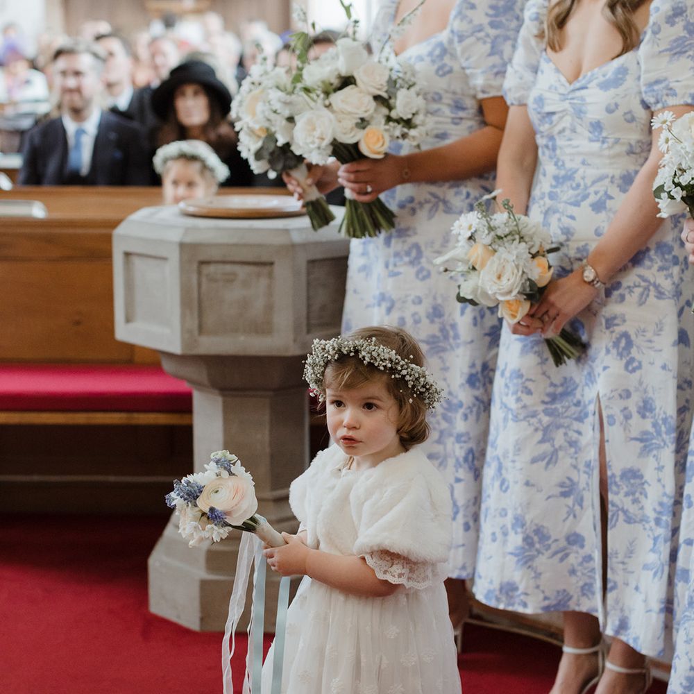 Flower girl in white dress with gypsophila flower crown and white faux fur shawl 
