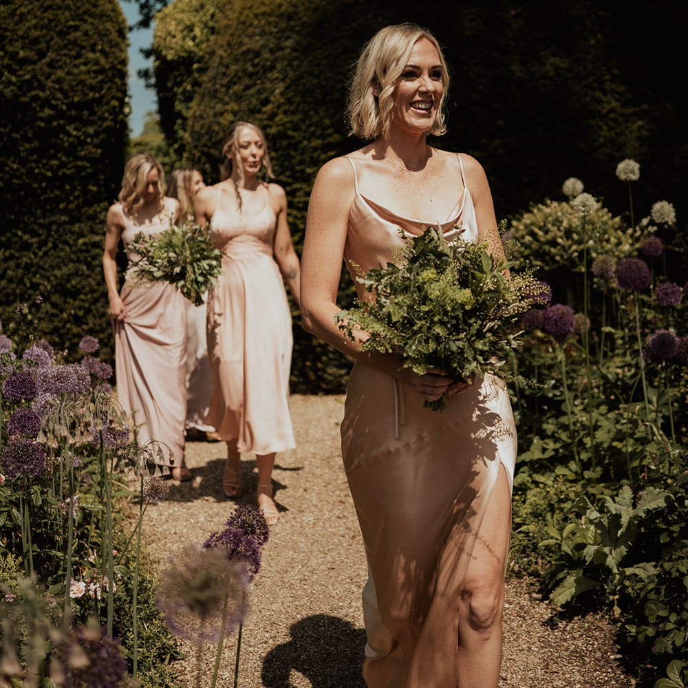 Bridesmaids holding green foliage bouquets in neutral dusky pink bridesmaid dresses 
