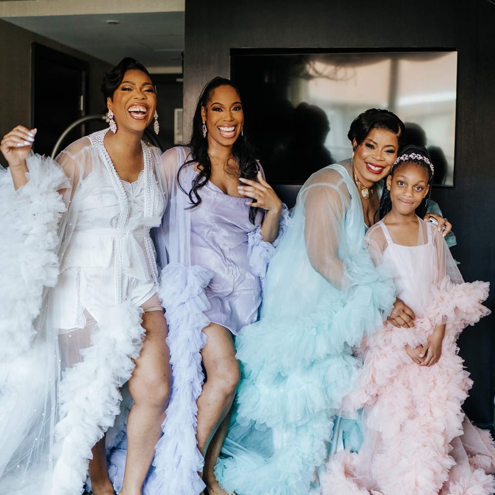 Bride in white sheer tulle and pearl bridal getting ready robe with bridesmaids and flower girl in mismatched pastel sheer tulle and pearl bridal getting ready robes