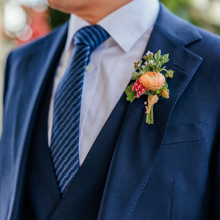 Groom wearing blue wedding suit with colourful flower buttonhole 