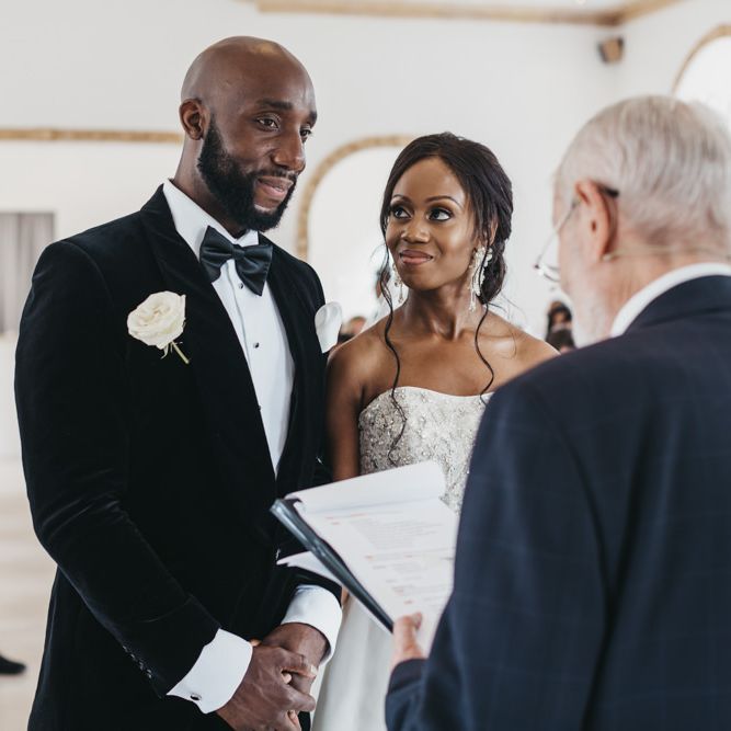 Black Bride and groom standing at the altar of Northbrook Park exchanging vows in a black tuxedo and strapless Oleg Cassini wedding dress