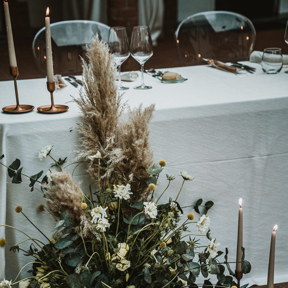 Unstructured wedding flower arrangement with foliage, white flowers, pampas grass and Billy Buttons 