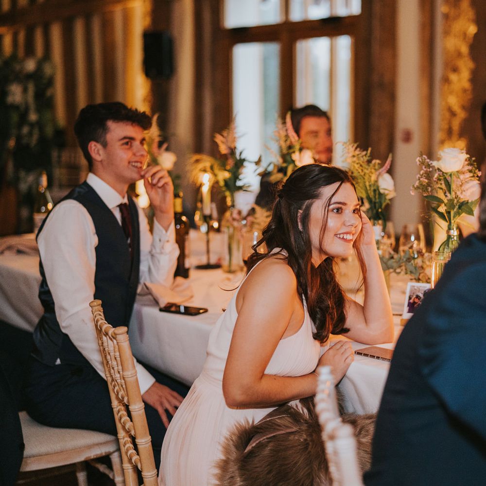 Wedding guests listen and laugh during reception speeches