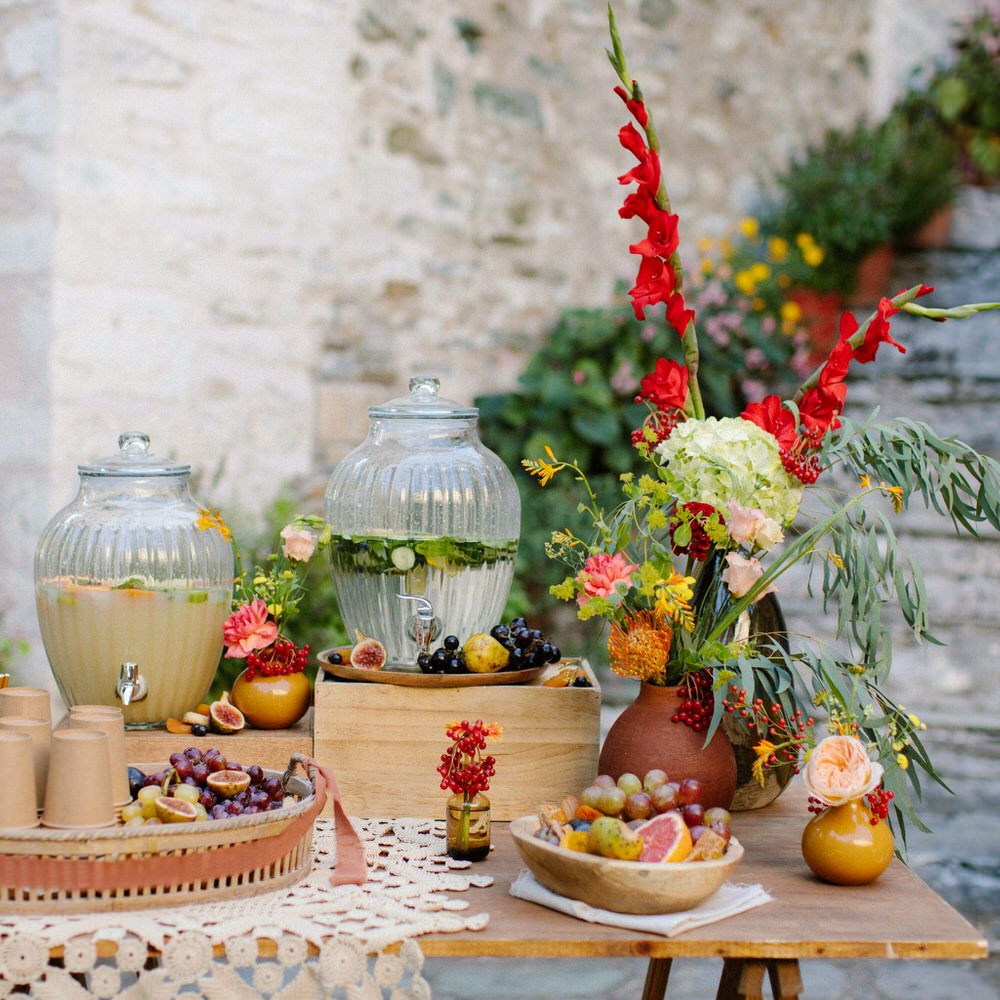 A small grazing table with fruit, fresh water and lemonade, with red and green flower decorations