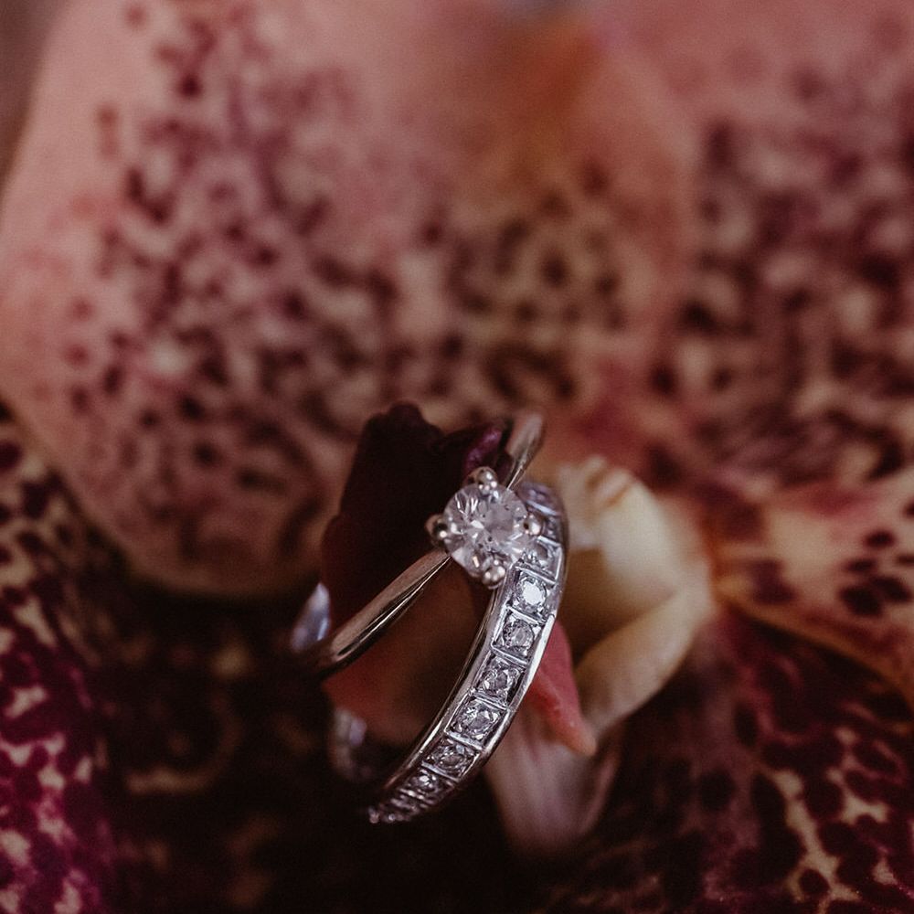 Close up of diamond wedding ring and diamond wedding band on a pink orchid