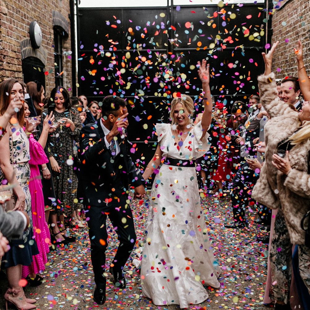 Colourful confetti moment at The Loft Studios London with bride in a ruffle sleeve wedding dress and groom in a wool suit 
