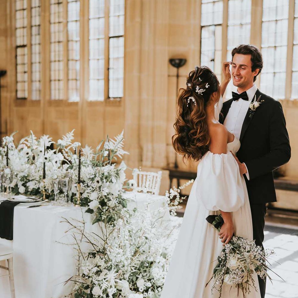 Bride with a wavy ponytail bridal up do caressing her grooms face at their monochrome Bodleian wedding 