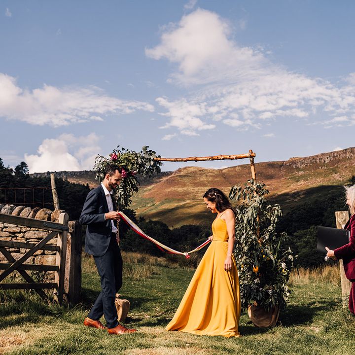 Bride & groom during handfasting ceremony outdoors on their wedding day