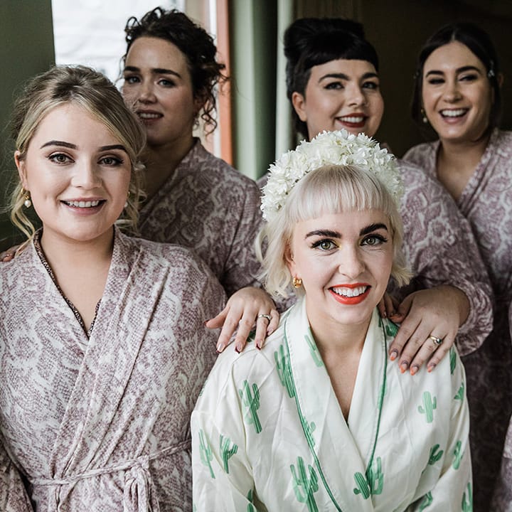 Bridesmaids in snake print robes with bride in cactus print robe as they get ready for the big day