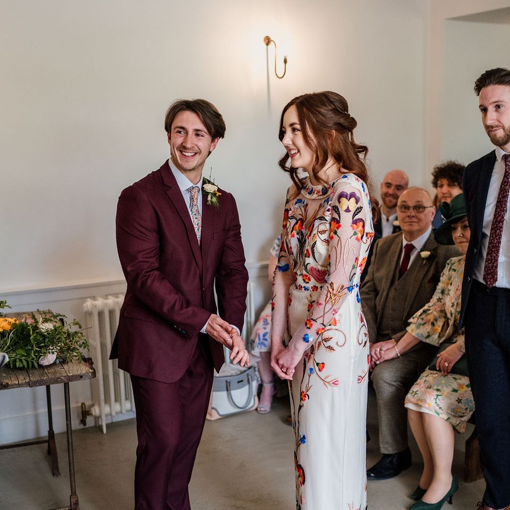 Bride in colourful and bright wedding dress and groom in burgundy three piece suit for wedding 