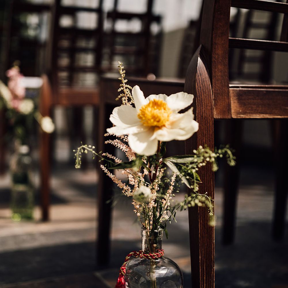 Glass bottle vase holding wedding flowers for aisle decoration 
