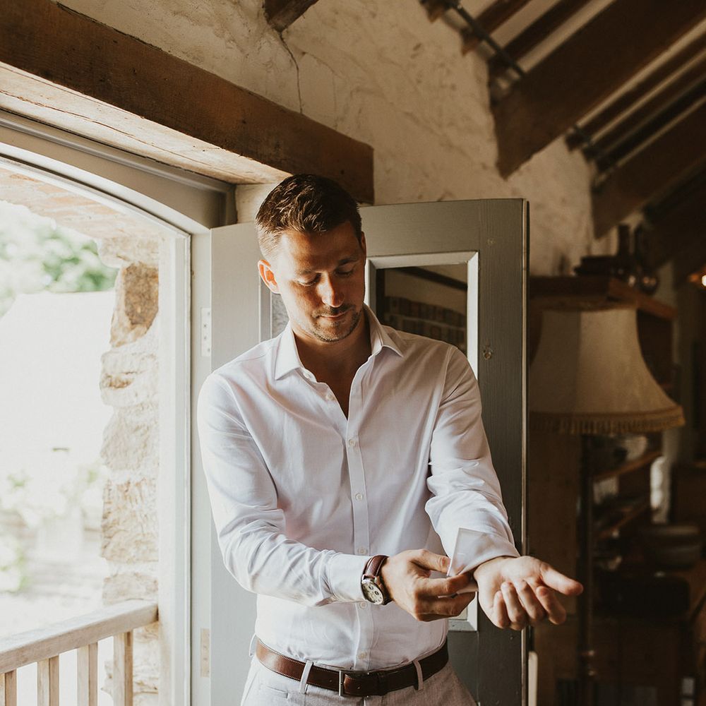 Groom puts on his cufflinks as he gets ready for the wedding 