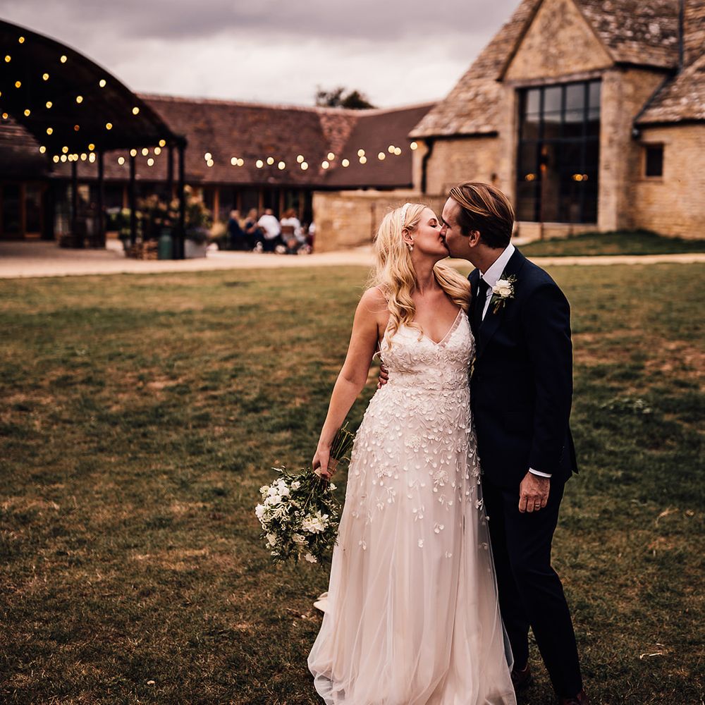 Bride in an appliqué floral Alexandra Grecco Lana wedding dress with the groom in a navy blue suit 