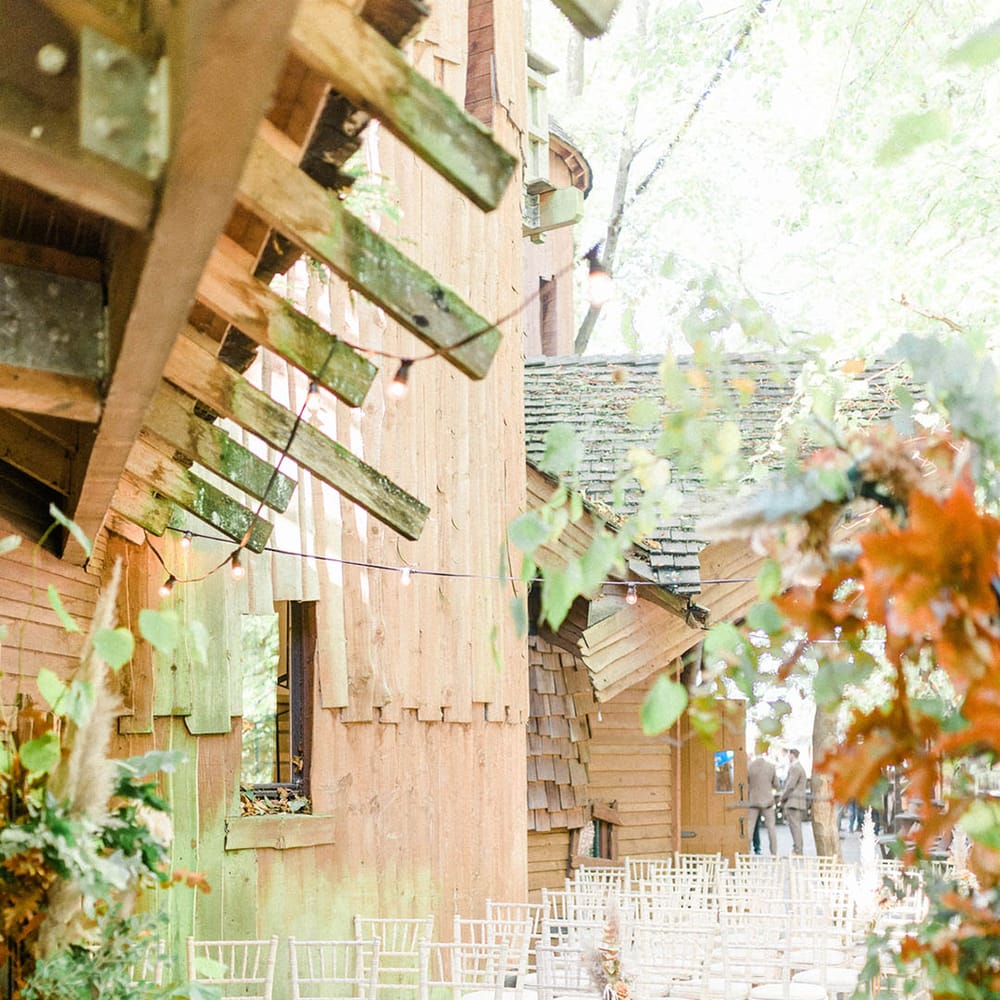White wicker chairs line the aisle at Alnwick Garden Treehouse finished with pumpkin decor and dried floral arrangements 