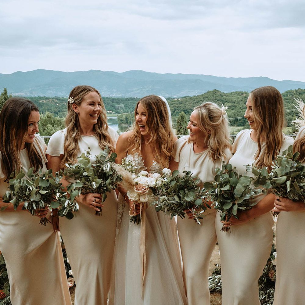 Bridal party wearing off white bridesmaids dresses and holding eucalyptus bouquets with bride in white tulle wedding dress at Italian wedding