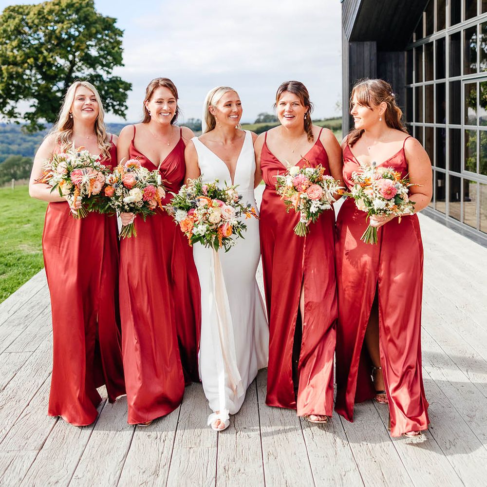 Bridesmaids in copper red satin bridesmaid dresses for autumn wedding at The Barn at Botley Hill 