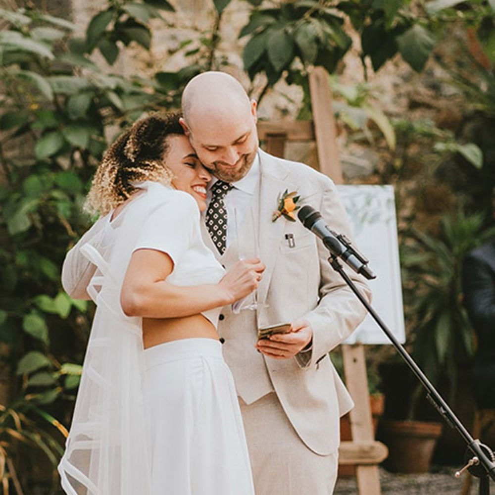 The bride rests her head on the groom's shoulder as they read out their joint wedding speech 