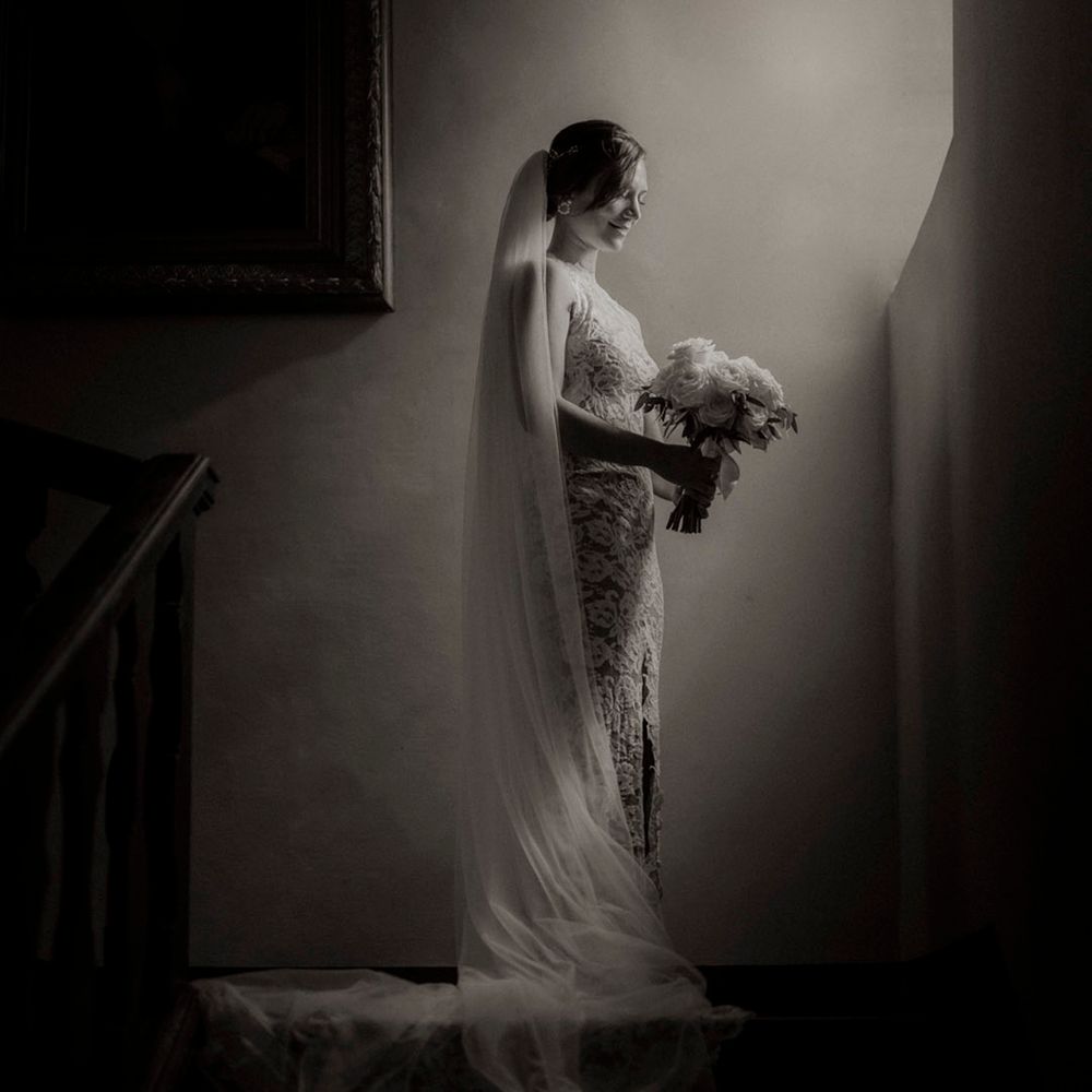 Bride in long sleeve lace wedding dress from Grace Loves Lace with long veil and white rose bouquet 