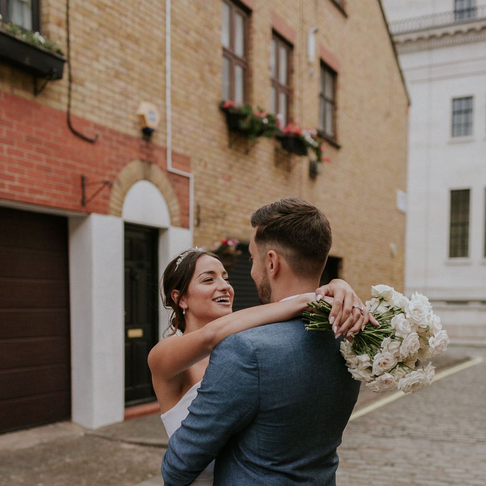Bride embracing her groom in blue suit
