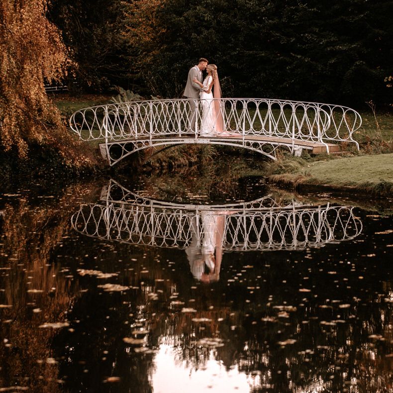 Bride and groom on the lakeside bridge at Preston Court