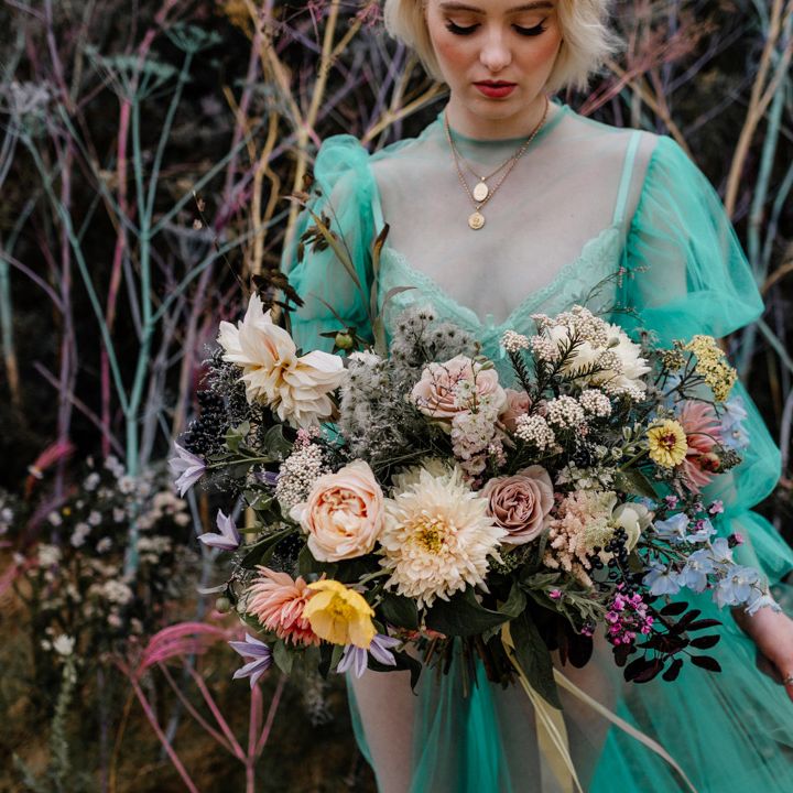 Bride holding a colourful rose, dahlia and foliage wedding bouquet 