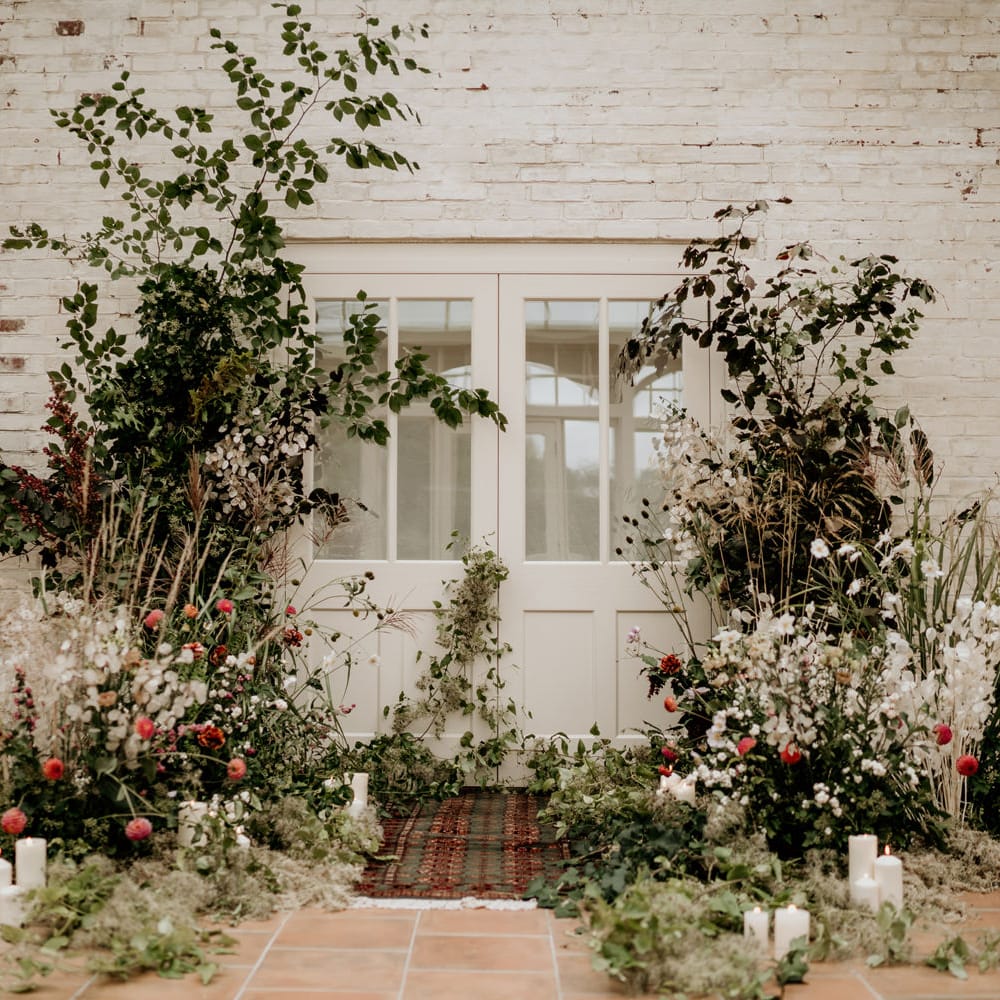 Wedding ceremony flowers at Our Beautiful Glasshouse in Sussex with wool rug 