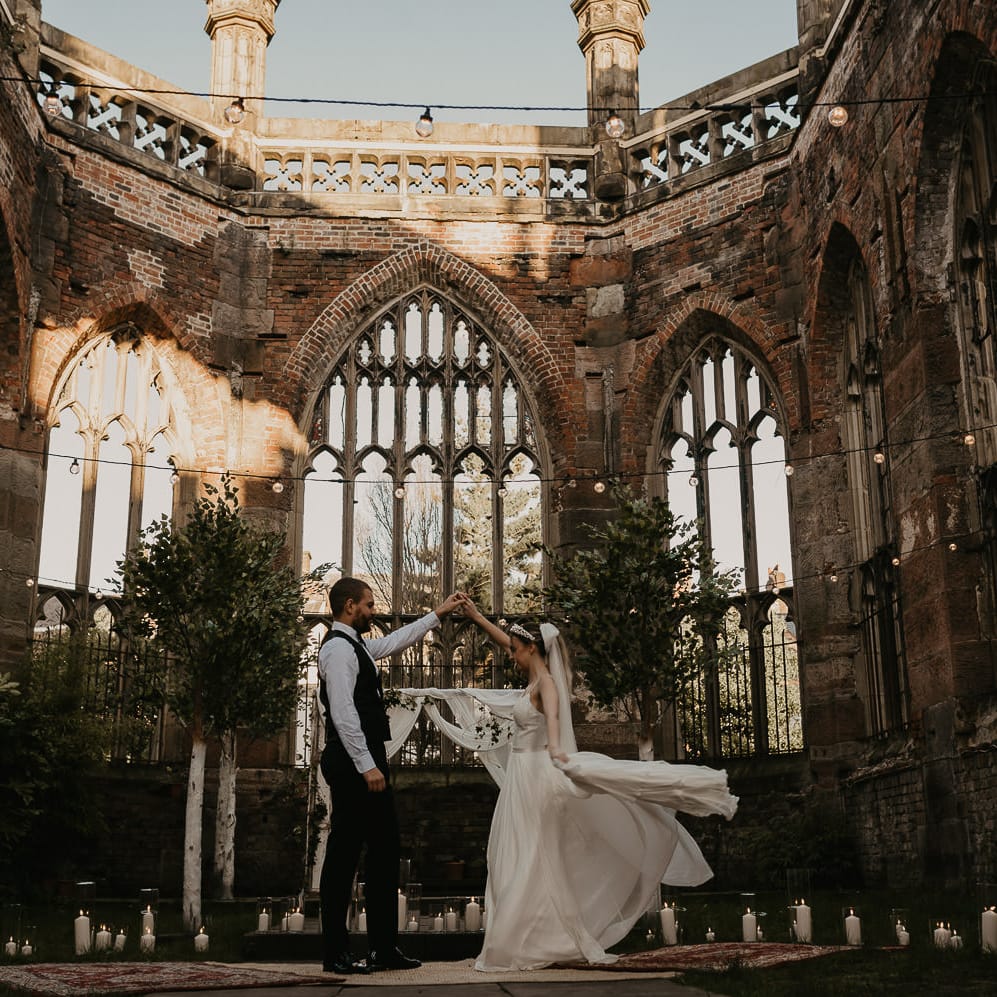 Bride and groom dancing on rugs under festoon lights at St Lukes Bombed Out Church in Liverpool 