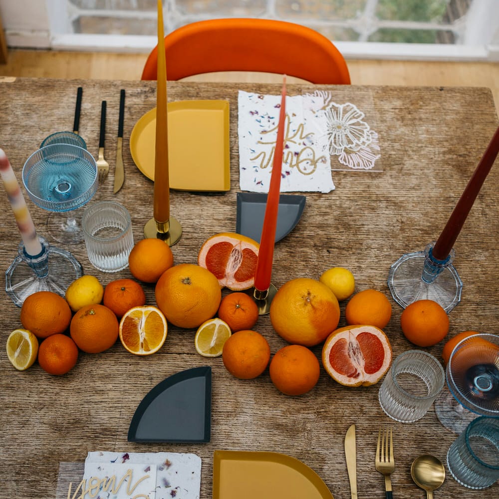 Minimal, retro inspired tablescape with gold, orange and mustard tones. Including citrus fruit centrepiece decoration and tapered candles