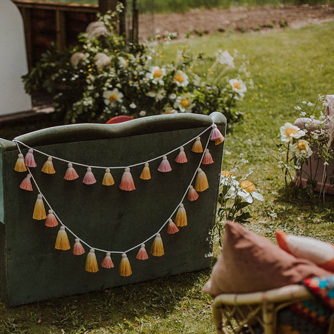 Green velvet retro sofa decorated with blush tissue tassels for sixties wedding
