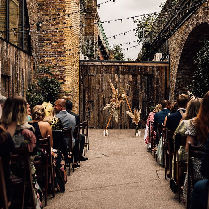 wedding ceremony in the courtyard at 100 Barrington with wooden triangle altar decorated in dried and fresh flowers 