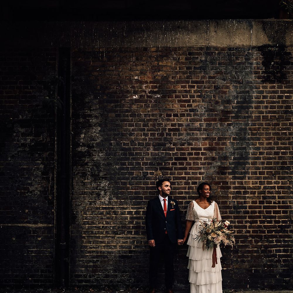 Urban wedding photograph with bride in a layered tulle wedding dress and groom in a navy suit 