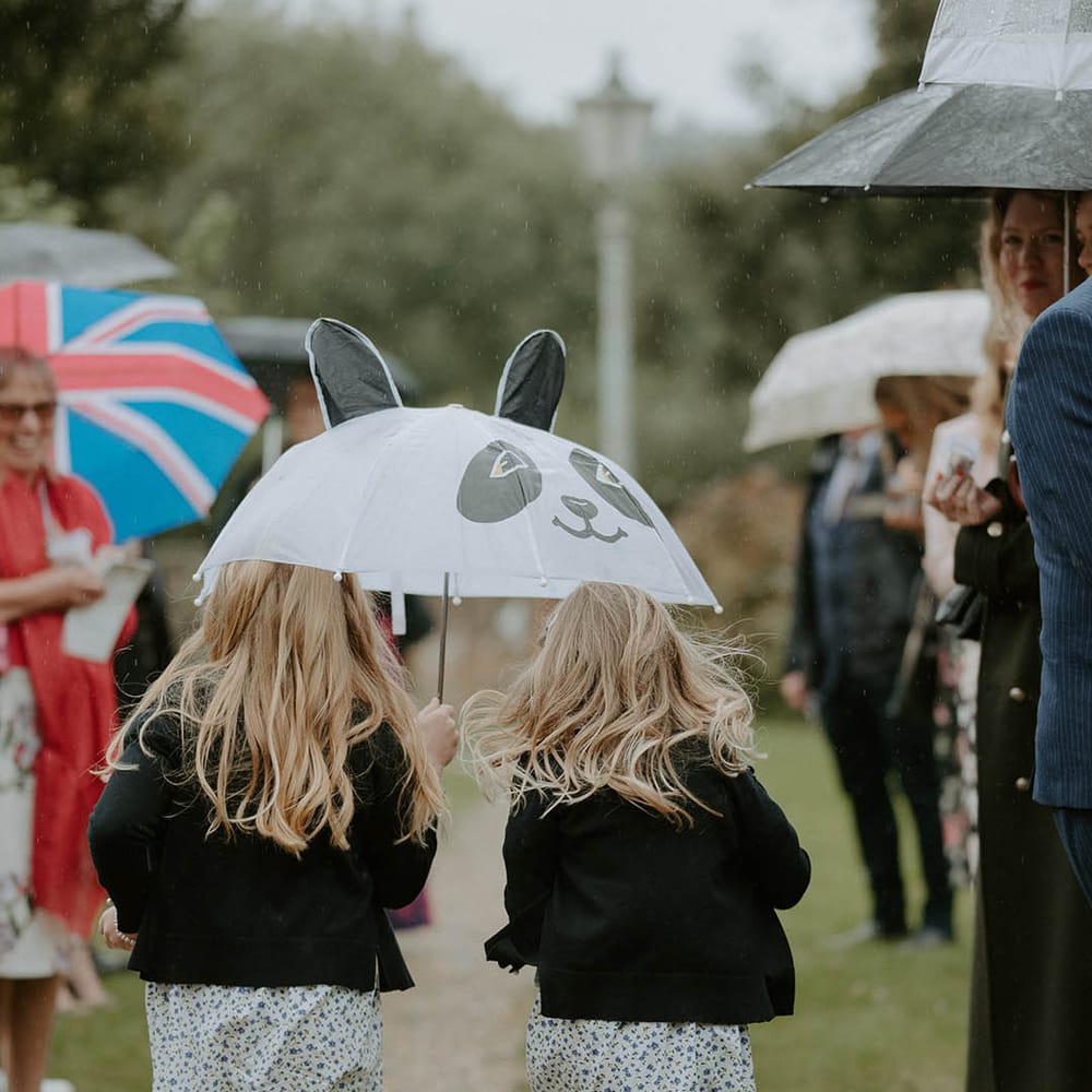 Children walk under umbrella at October wedding