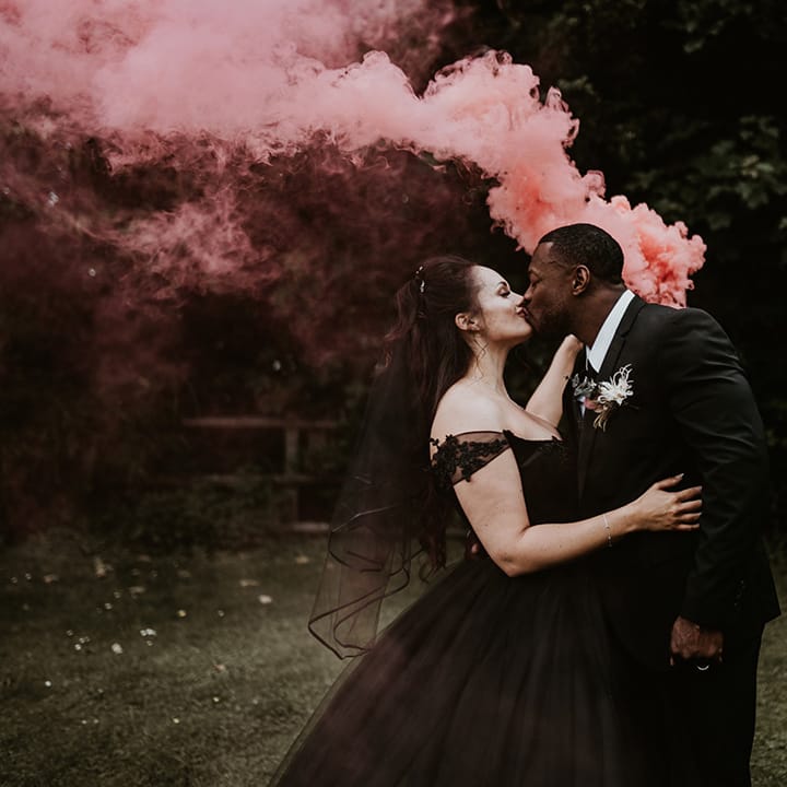 Bride & groom hold pink smoke bomb 