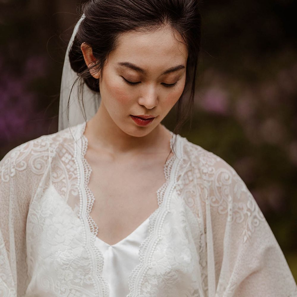 East Asian bride in a lace kimono style wedding dress tied with a yellow ribbon with natural makeup 