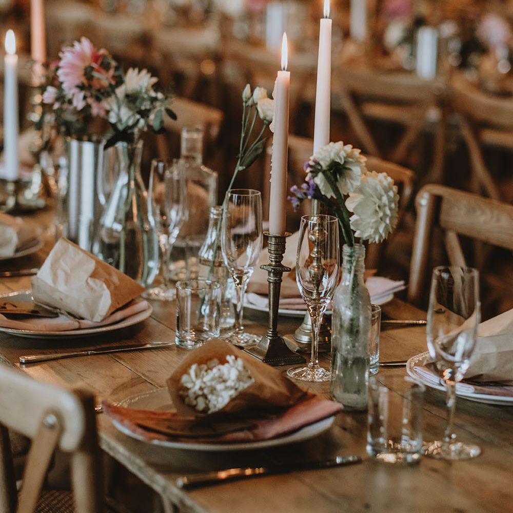 Rustic tablescape with vintage brass candle holders, avocado dyed napkins and popcorn favours in brown paper bags 