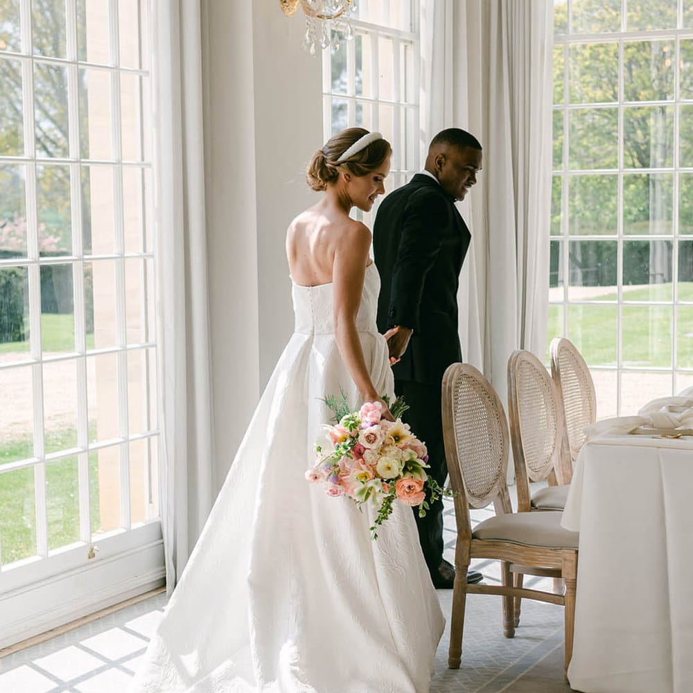 Bride and groom walk into Rushton Hall to take their seats together 