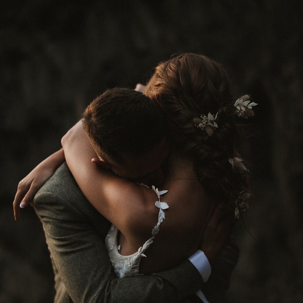 Bride wears floral embellished wedding dress and holds her groom in intimate image on their wedding day