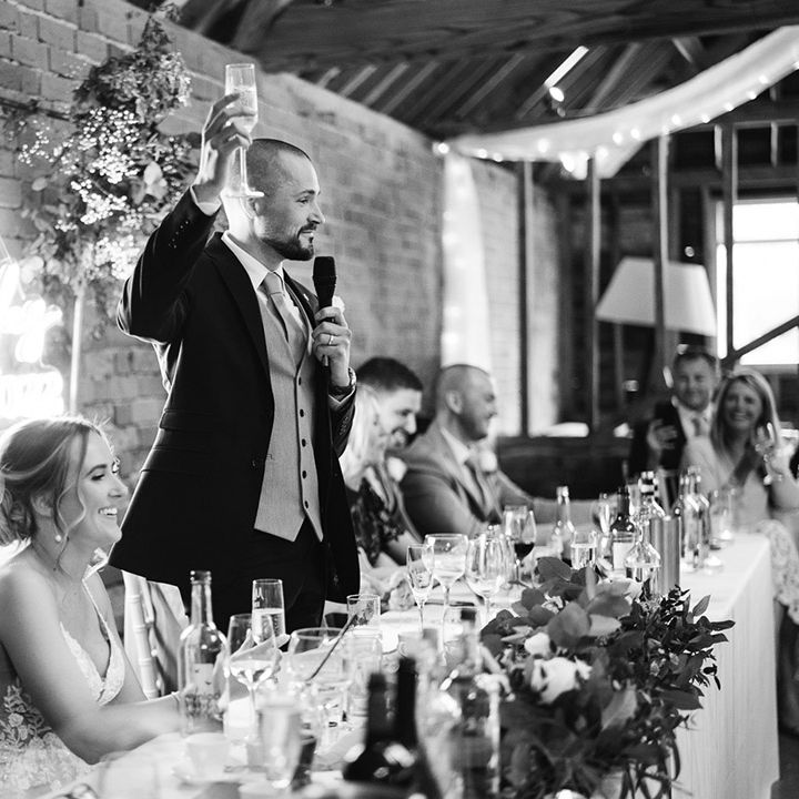 Groom raises his glass in a toast as he reads out his wedding speech