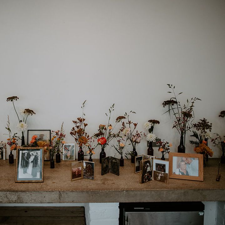 Small floral arrangements in brown medicine bottles beside personal photos 